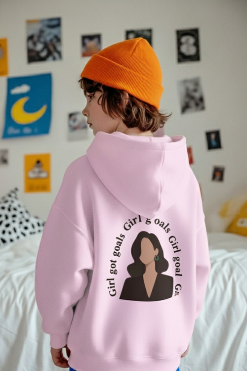 Person wearing a pink hoodie with a graphic design in a bedroom setting