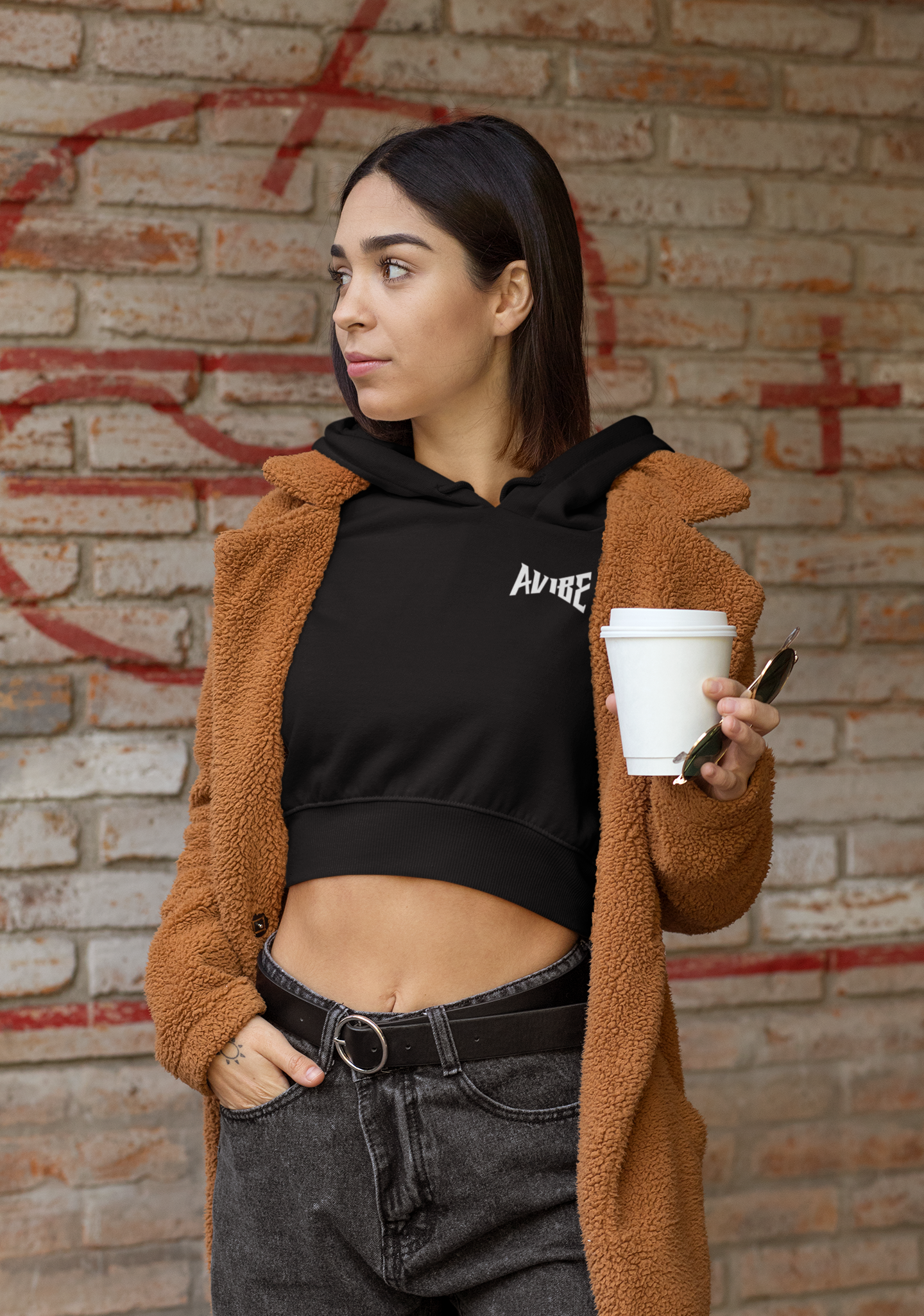 Woman holding a coffee cup against a brick wall