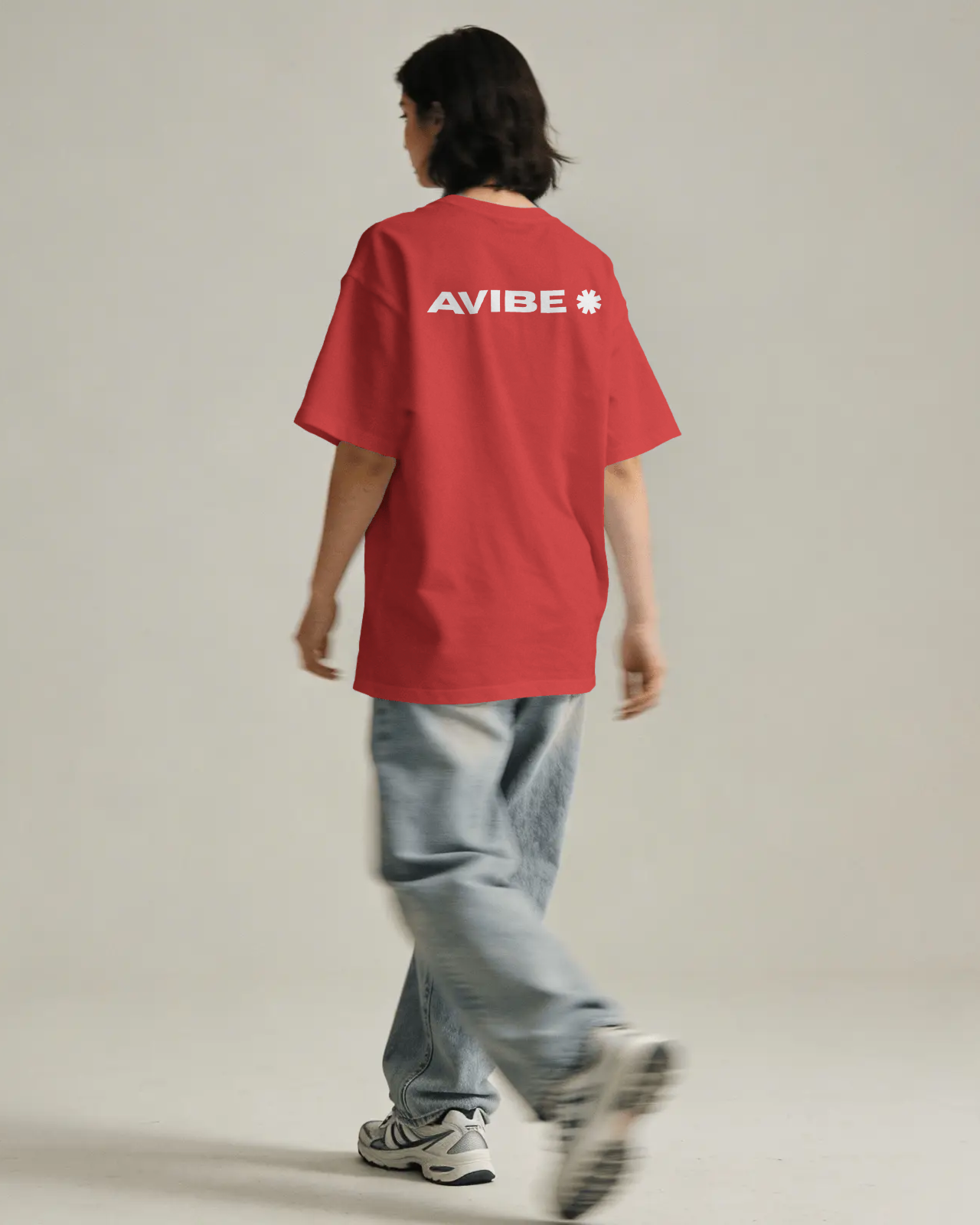Person wearing a red t-shirt with 'AVIBE' logo on the back, walking away against a plain background