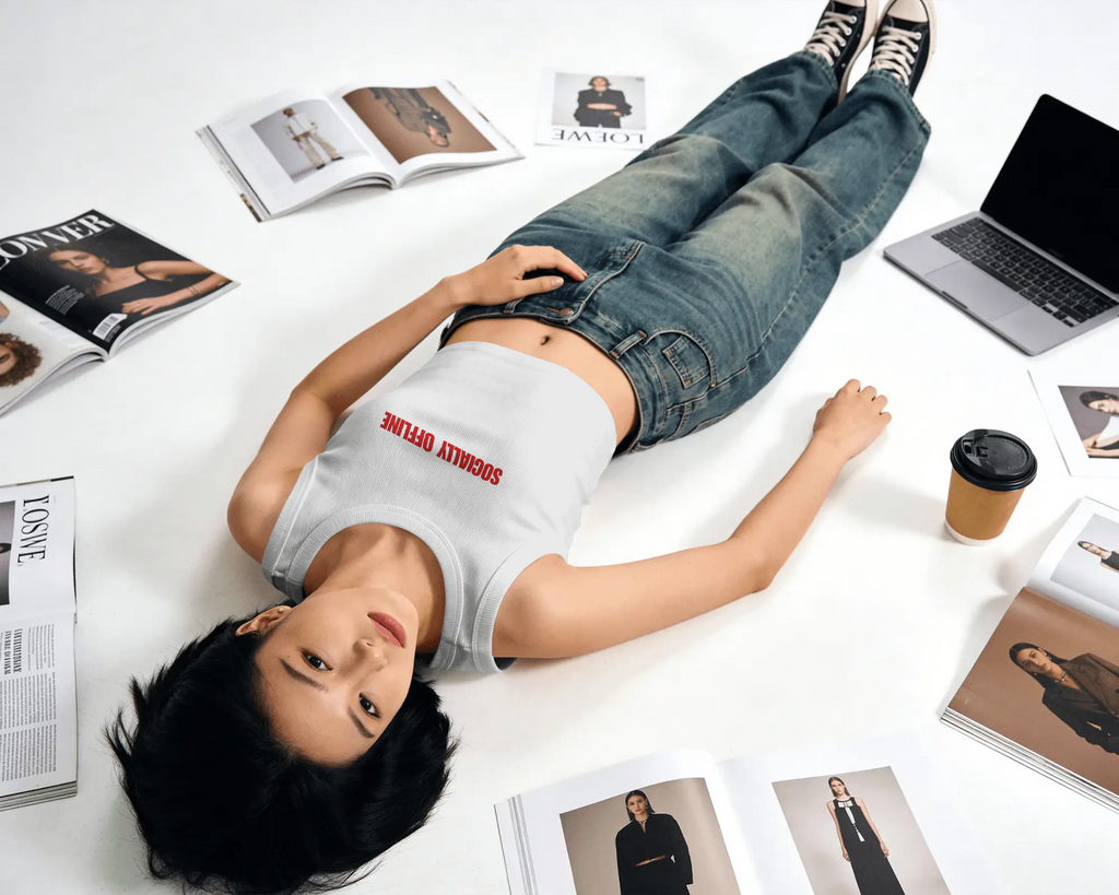Person lying on a white floor with books, a laptop, and a coffee cup around them.