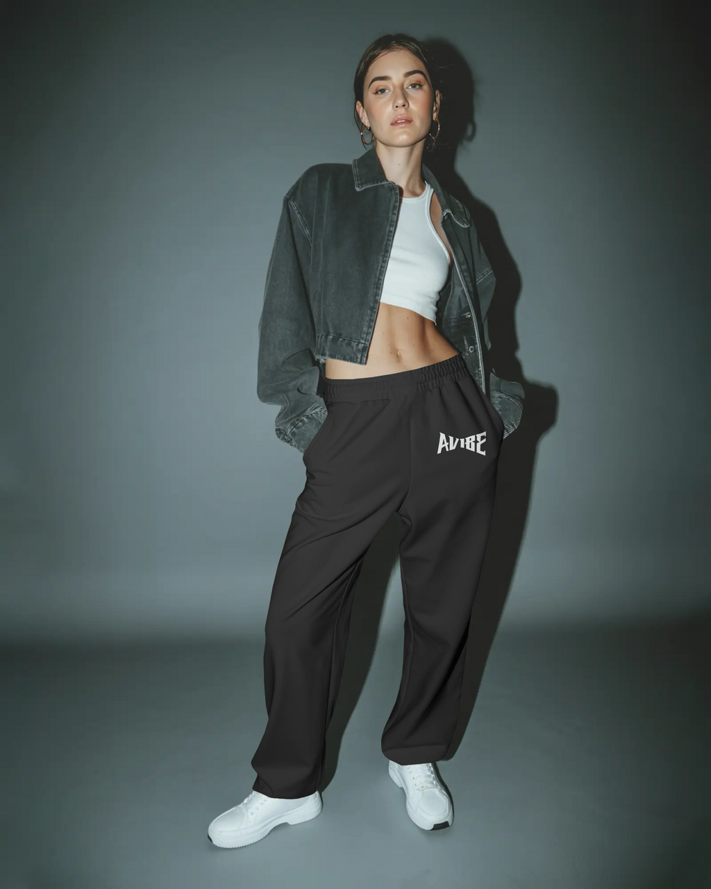 Person wearing a green jacket, white top, and black pants with 'Aurelie' branding on a gray background